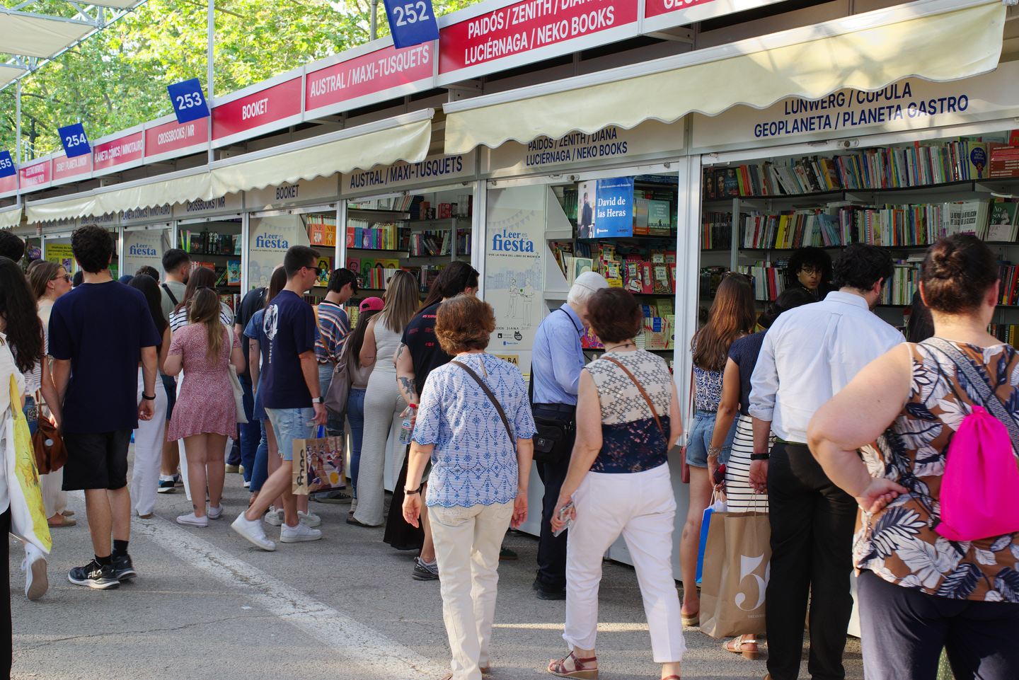 Lectores ante las casetas de la Feria del Libro en el parque del Retiro
